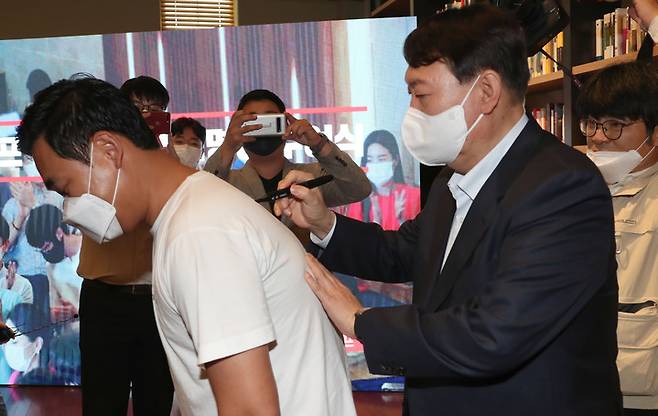 [서울=뉴시스] 국회사진기자단 = 국민의힘 대권주자인 윤석열 전 검찰총장이 3일 서울 강남구 최인아책방에서 열린 국민캠프 청년위원회 임명장 수여식에서 한 참석자의 등에 사인을 해주고 있다. 2021.10.03. photo@newsis.com
