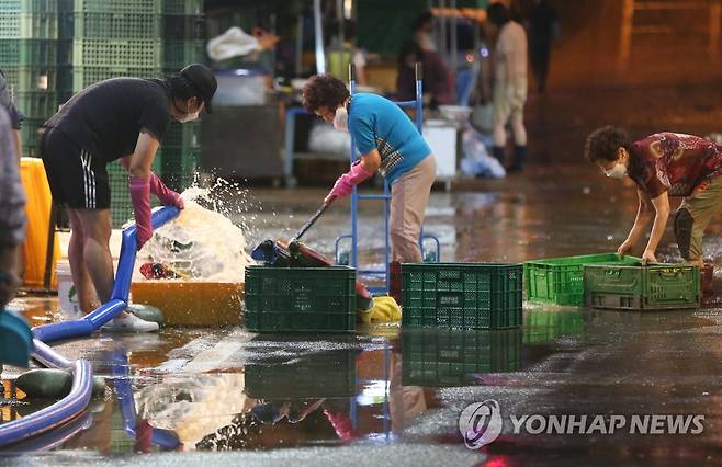 제12호 태풍 '오마이스'가 울산을 지나간 8월 24일 오전 중구 태화시장이 많은 비로 침수돼 상인들이 흙탕물을 씻어내고 있다.