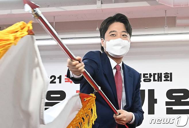 이준석 국민의힘 신임 대표가 11일 서울 여의도 국민의힘 당사에서 열린 전당대회에서 당선 확정 후 당기를 흔들고 있다. 2021.6.11/뉴스1 © News1 오대일 기자