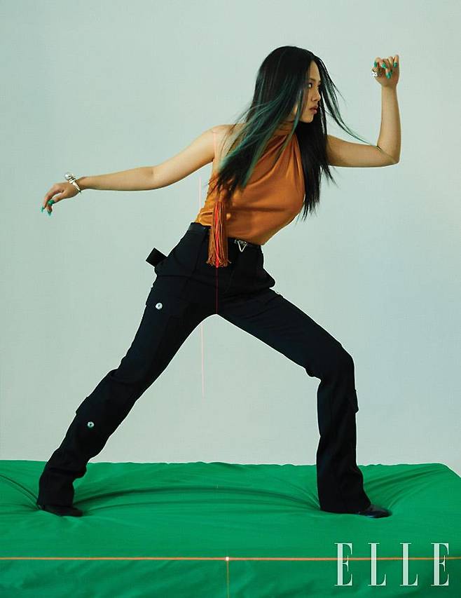 프린지 장식을 더한 홀터넥 톱과 블랙 팬츠, 트라이앵글 버클의 벨트, 부츠, 뱅글, 링은 모두 Bottega Veneta.