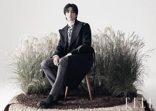 와이드 라펠 장식의 네이비 롱 코트와 크림 컬러 터틀넥 풀오버, 프린트 셔츠, 그레이 팬츠, 로고 장식의 앵클부츠는 모두 Dior Men.