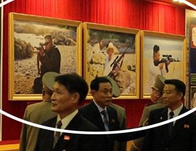 북한이 10월 11일 개최한 국방발전전람회 '자위-2021'에서 김정은 국무위원장의 사격 사진 세 점(흰색 원)이 공개됐다. 조선중앙통신이 12일 공개한 사진에 따르면 전람회장 내부에 김 위원장은 야외에서 흰색 또는 검은색 인민복을 입고 조준경이 부착된 소총을 들거나 겨누는 사진이 걸렸고 참석자들이 이를 관람했다. 조선중앙통신 홈페이지 캡처=연합뉴스