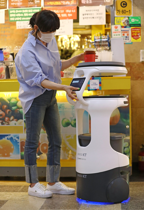 A robot delivers coffee at a ceremony to kick off the AI 5G-based Service Robot Project, held in the underground shopping area of Jungangno Station in Daejeon, on Wednesday. As part of the project, two delivery robots will deliver coffee in the shopping area starting early next year. Other robots will be used to disinfect and patrol the area starting at the end of this year. [YONHAP]