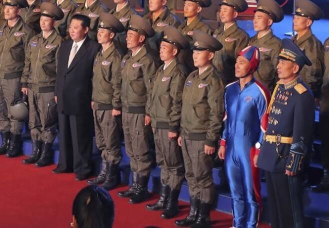 김정은 북한 국무위원장(앞줄 왼쪽 세번째)이 지난 11일 국방발전전람회 개막식에서 에어쇼를 펼친 파일럿들과 기념촬영을 하고 있다. 앞줄 오른쪽 두번째의 파란색 전신 타이즈 차림 남성이 시선을 확 끈다. 조선중앙통신 제공, 연합뉴스