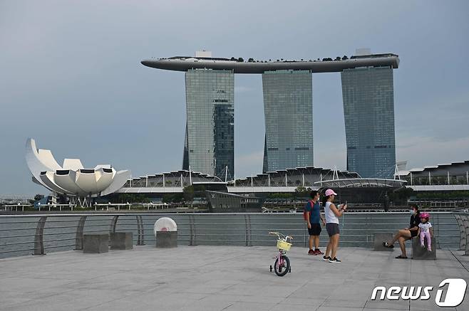 13일(현지시간) 싱가포르 마리나베이샌스 호텔(오른쪽)과 아트사이언스 박물관(왼쪽)이 보이는 공원에서 사람들이 사진 촬영을 하고 있다. 2021.10.13 © AFP=뉴스1