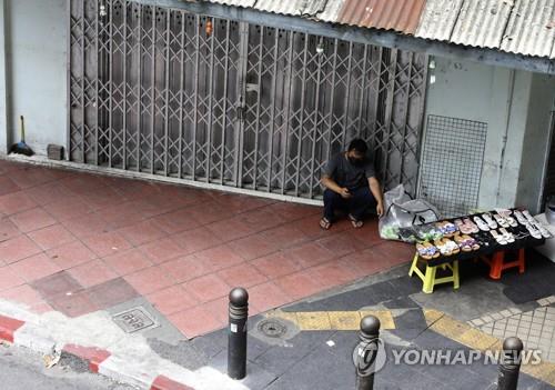 봉쇄 조치로 문을 닫은 방콕 시내 상점 앞에서 손님을 기다리는 노점상. 2021.7.12 [EPA=연합뉴스]
