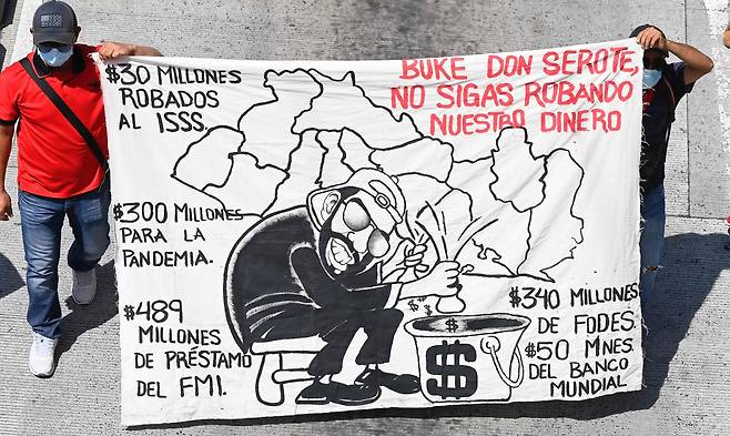 두 명의 시위대가 나이브 부켈레 대통령의 비트코인 등 경제정책을 비난하는 그림을 들고 시위에 참여하고 있다. AFP=연합뉴스