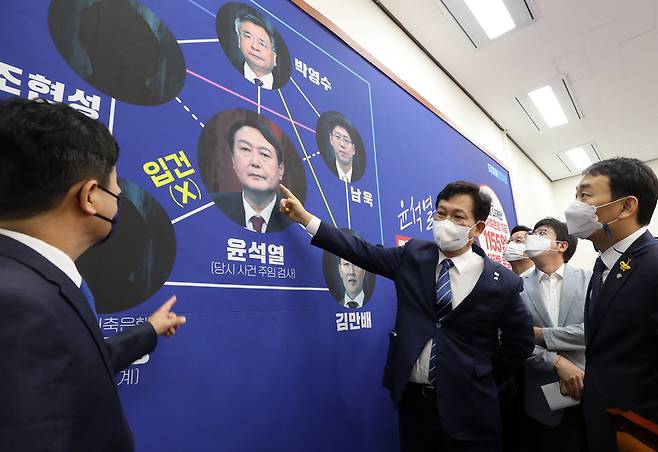 더불어민주당 송영길 대표와 최고위원들이 18일 오전 국회에서 열린 최고위원회의에 앞서 대장동 개발 의혹 관련, 부산저축은행 수사를 지적하는 내용이 담긴 배경판을 바라보며 대화를 나누고 있다. / 사진 = 국회사진기자단