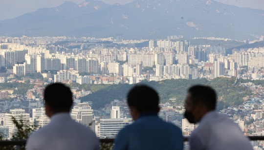 시민들이 서울 남산에서 서울 시내 아파트를 내려다보며 대화하고 있다. <연합뉴스>