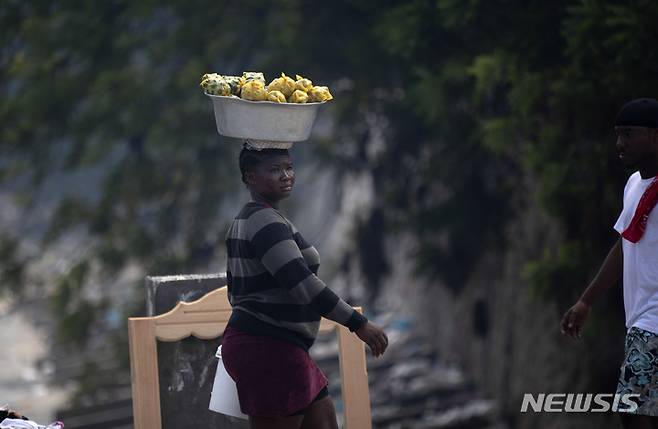 [포르토프랭스=AP/뉴시스] 17일(현지시간) 아이티 포르토프랭스에서 한 노점상이 머리에 물건을 이고 이동하고 있다. 아이티에서 보육원을 짓고 귀국하던 17명의 미국 선교사가 무장단체에 납치됐으며 이 중엔 어린이도 포함된 것으로 알려졌다. 아이티에서는 올 8월까지 총 328명이 납치돼 2020년 한 해 동안 납치됐던 238명의 기록을 훌쩍 뛰어넘었다. 2021.10.18.