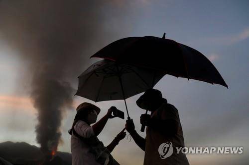 비가 내리지 않아도 우산은 필수 (타후야 로이터=연합뉴스) 18일(현지시간) 스페인령 카나리아제도 라팔마섬 주민들이 화산재를 피하기 위해 우산을 쓰고 있다. 2021.10.20 photo@yna.co.kr