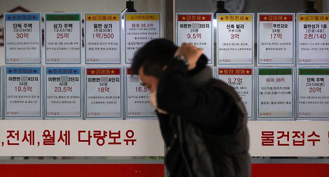 지난 19일 매물 정보가 붙어 있는 서울 시내 한 공인중개사무소 앞을 한 시민이 지나고 있다. 최근 집값 오름세가 다소 주춤하자 집값 하락이 시작됐는지를 놓고 시장에서 의견이 분분하다.  연합뉴스