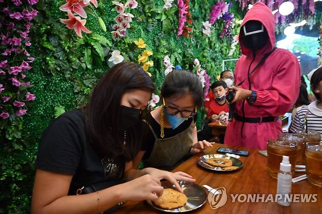 인도네시아 수도 자카르타의 한 카페에서 고객들이 '오징어게임'에 나오는 '달고나 뽑기'에 열중하고 있다.[AFP=연합뉴스]