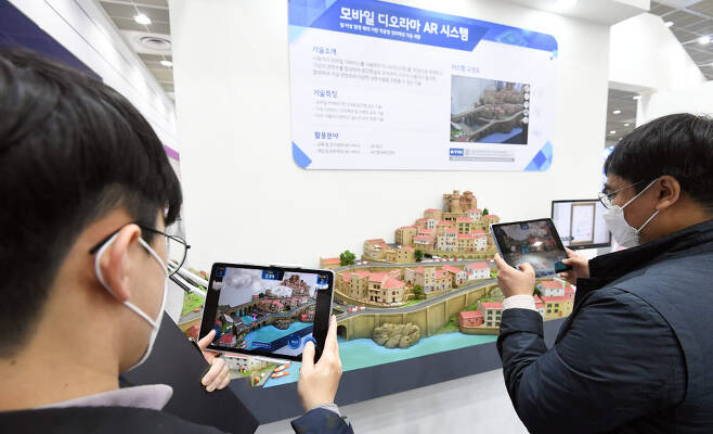 참관객들이 한국전자통신연구원 부스에서 모바일 디오라마 AR시스템을 체험하고 있다.