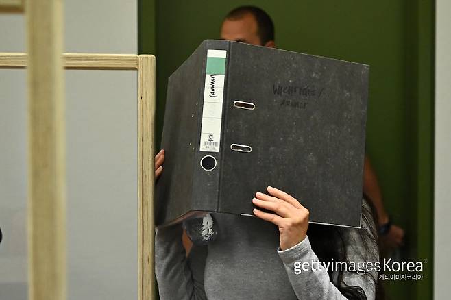 제니퍼 위니시가 지난 13일 독일 뮌헨 법원에 출석하면서 파일로 얼굴을 가리고 있다. | 게티이미지