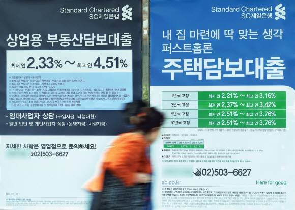 금융 당국이 ‘가계부채 관리 강화방안’을 발표한 26일 한 시민이 경기도의 한 시중은행 앞에 내걸린 부동산담보대출 상품 광고 앞을 지나가고 있다.박지환 기자 popocar@seoul.co.kr