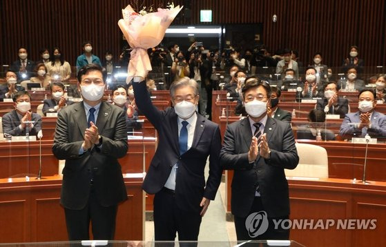 이재명 민주당 대선 후보가 지난 15일 오전 서울 여의도 국회에서 열린 민주당 의원총회에 참석해 꽃다발을 들어올리며 인사하고 있다. 왼쪽부터 송영길 대표, 이 후보, 윤호중 원내대표. 국회사진기자단