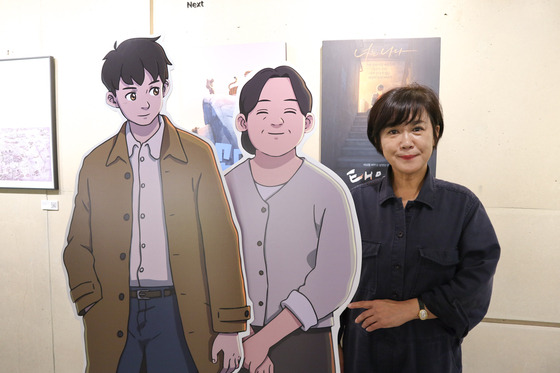 Myung Films CEO Shim Jae-myung poses with cutout cardboard characters from upcoming animated film "Chun Tae-il," based on the labor activist Chun Tae-il (1948-70). [MYUNG FILMS]