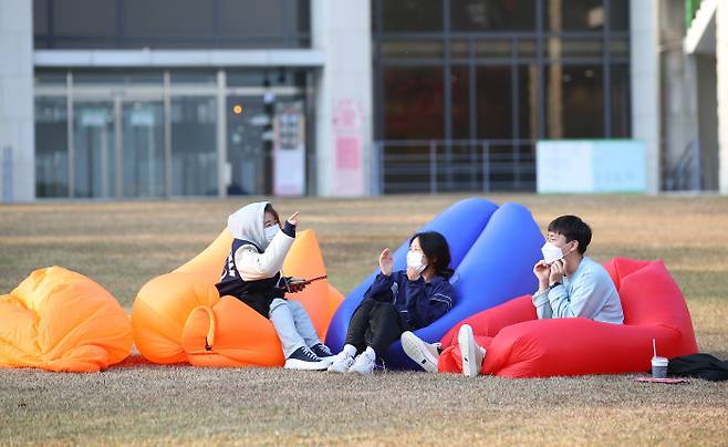 단계적 일상회복(위드 코로나) 시행 첫날인 1일 서울 시내의 한 대학교에서 학생들이 캠퍼스 잔디밭에 설치된 에어 소파에서 휴식을 취하고 있다.연합뉴스