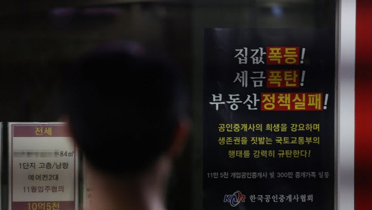 한 시민이 부동산공인중개업소 매물정보 게시판에 붙어있는 정부 부동산 정책 규탄 포스터를 보고 있다. <연합뉴스>