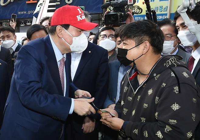 국민의힘 대선 경선 후보인 윤석열 전 검찰총장(왼쪽)이 3일 서울 중구 남대문시장을 방문해 선물 받은 모자를 쓰고 상인과 대화하고 있다. 국회사진기자단