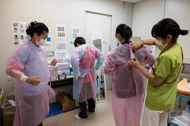 지난 6월 15일 일본 가와사키시 소재 성마리안나 대학병원 미화원들이 코로나19 병동에 들어가기 전에 보호복을 입고 있다. 가와사키=AFP 연합뉴스