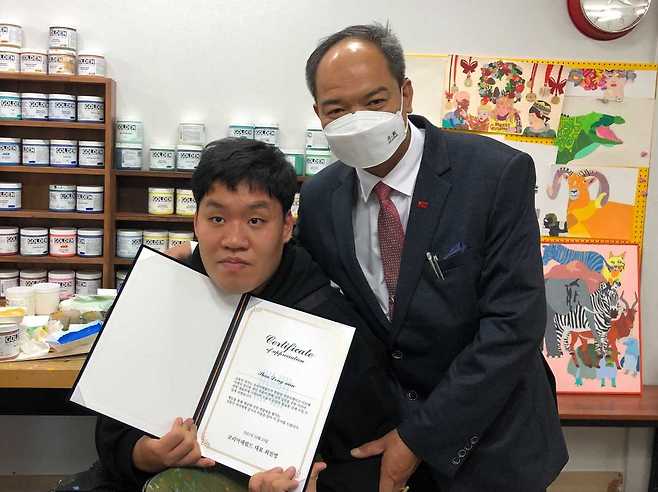 Artist Shin Dong-min (left), holding his certificate of appreciation, and Yan Naing Htun, special representative of the Federal Republic of Myanmar, pose together at the donation ceremony.