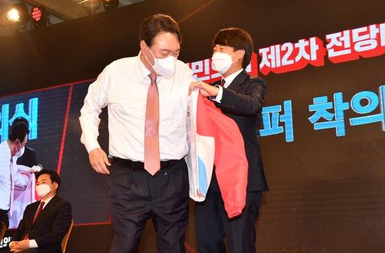 국민의힘 대선 후보로 윤석열 전 검찰총장이 선출됐다. 압도적인 당원들의 지지로, 막판까지 경쟁한 홍준표 의원을 눌렀다. 5일 후보 확정 발표 뒤, 이준석 국민의힘 대표가 윤 전 총장에게 당 점퍼를 입혀주고 있다. 국회사진기자단