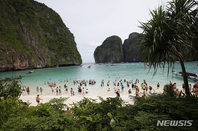 [끄라비(태국)=AP/뉴시스]2018년 5월31일 관광객들이 태국 끄라비 지방의 피피섬 마야 베이 해변을 걷고 있다. 2021.11.16