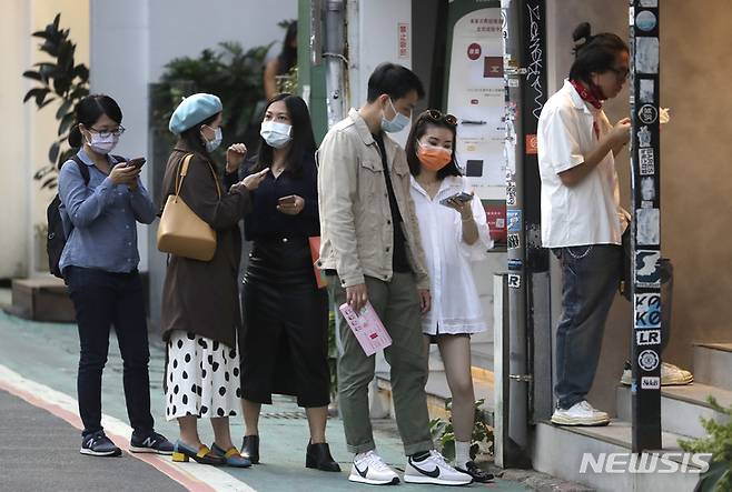 [타이베이=AP/뉴시스] 대만 수도 타이베이 시내에서 21일 전문점에 들어가 쇼핑하려는 손님들이 코로나19 예방을 위해 마스크를 쓴 채 줄을 서서 기다리고 있다. 2021.11.21