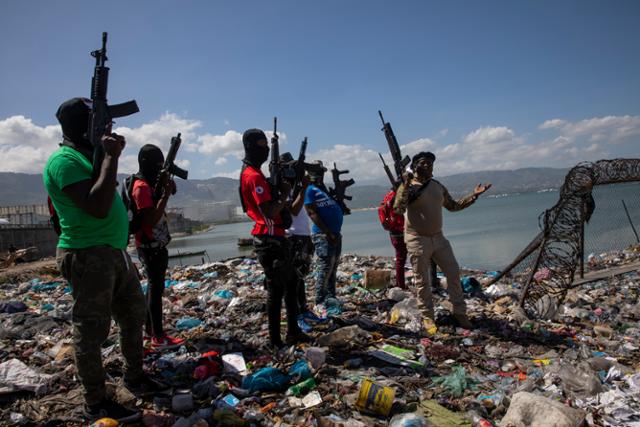 아이티의 한 갱단 조직원들이 지난달 무장한 채 수도 포르토프랭스의 바닷가에서 총기를 들고 서 있다. 포르토프랭스=AP 연합뉴스