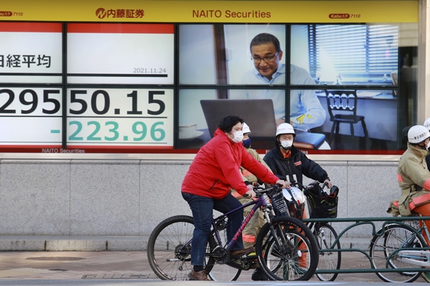 24일 일본 도쿄의 한 증권사 전광판 앞에 마스크를 쓴 시민들이 자전거를 타고 신호 대기중이다./AP연합뉴스
