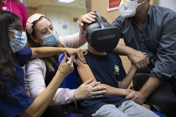 이스라엘 서부 라마트간에서 22일(현지시간) 8세 아동이 가상현실(VR) 헤드셋을 착용한 채 화이자와 바이오엔테크의 코로나19 백신을 접종받고 있다.AP뉴시스