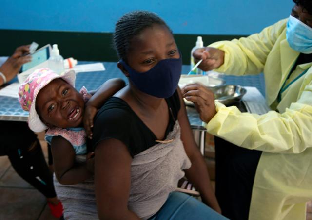 10월 21일 남아프리카공화국 요하네스버그 인근에서 아기를 업은 한 여성이 화이자 코로나19 백신을 접종하는 모습. 요하네스버그=AP 뉴시스
