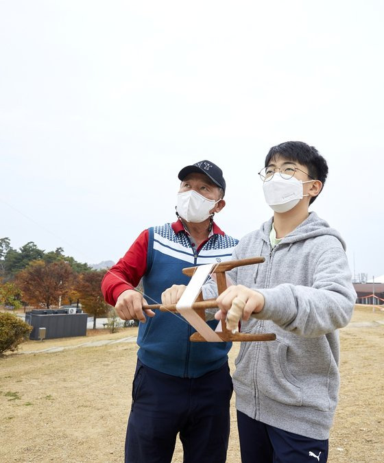 유병찬 대표가 김재신 학생기자에게 얼레를 잘 조절하는 방법을 설명했다. 얼레에서 실을 풀면 연이 바람의 방향에 따라 날게 되고, 감으면 위로 뜬다.