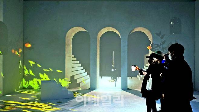 문준용의 미디어아트 ‘어그먼티드 섀도: 별을 쫓는 그림자들’에 참여한 관람객들. 그림자들이 빛을 얻어 만든 벽 안쪽으로 입체감이 열리는 중이다. 작품은 컵처럼 생긴 손전등을 든 한 사람이 이야기를 진행하고 다른 사람들은 그 장면을 바라보며 감상할 수 있도록 제작됐다(사진=오현주 문화전문기자).