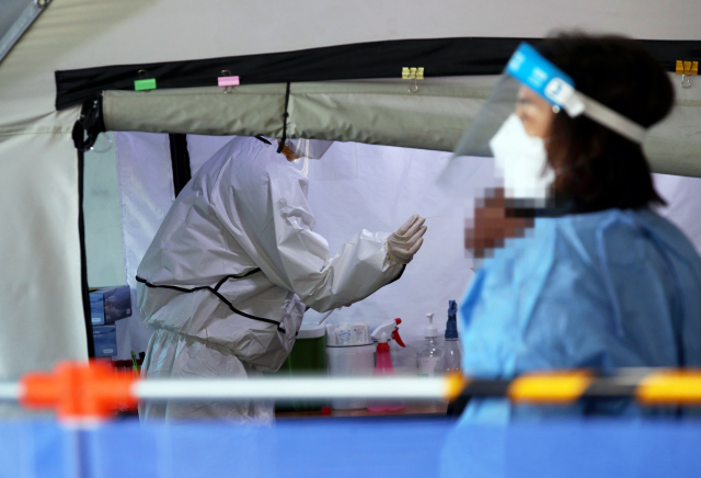 보건소 선별진료소에서 의료진이 코로나19 검사를 받는 시민의 검체를 채취하고 있다./연합뉴스