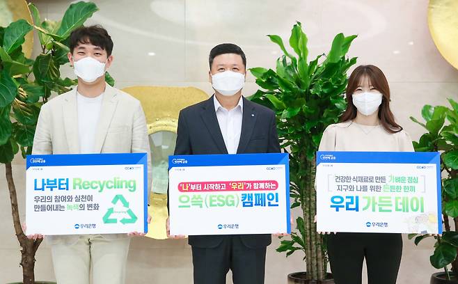Woori Bank CEO Kwon Kwang-seok (center) and employees hold signs promoting intra-company ESG campaigns at the lender’s headquarters in central Seoul, in this photo released on Oct. 19. (Woori Bank)