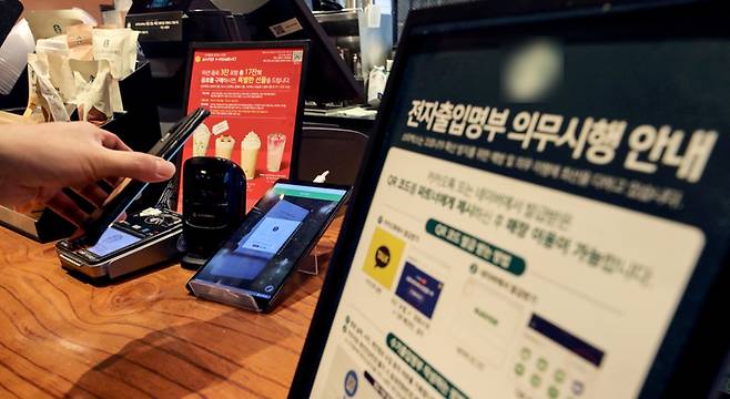 [서울=뉴시스] 김병문 기자 = 6일부터 4주 동안 사적모임 최대 인원이 수도권 6명, 비수도권 8명으로 제한된다. 또 식당과 카페를 비롯한 각종 실내 다중이용시설로 방역패스 적용이 확대됐다. 이에 따라 식당·카페를 비롯해 학원, PC방, 영화관, 공연장, 도서관, 독서실, 스터디카페, 박물관, 미술관 등을 이용할 때는 백신 접종완료일로부터 2주(14일)가 지났다는 증명서나 PCR 음성확인서가 필요하다. 사진은 6일 오전 서울 시내 한 카페를 찾은 한 시민이 QR코드를 등록하고 있다. 2021.12.06. dadazon@newsis.com