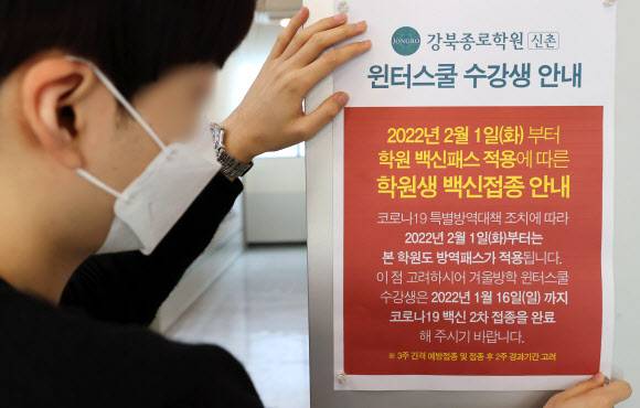 학원까지 확대되는 방역패스 적용 - 7일 서울 마포구 종로학원 강북본원에서 직원이 방역패스 관련 안내문을 부착하고 있다.      정부가 학생과 학부모들의 반발에도 내년 2월부터 식당?카페?학원?도서관 등을 이용하는 12~18세 청소년에게도 방역패스를 적용한다고 밝히면서, 학생과 학부모들을 중심으로 ‘미접종자에 대한 차별이자 학습권 침해, 사실상 접종 강요’라는 움직임이 거세지고 있다. 2021.12.7 연합뉴스