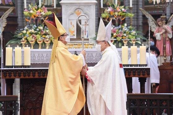 염수정 추기경(오른쪽)이 후임 서울대교구장 정순택 대주교에게 주교의 품위와 관할권을 상징하는 목장을 넘겨주고 있다. [사진 천주교 서울대교구]