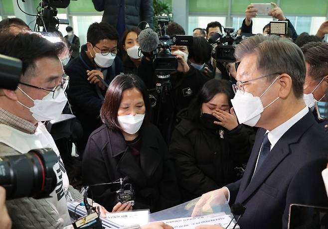 더불어민주당 이재명 대선후보(오른쪽)가 8일 오후 국회 의원회관 3층 전시공간에서 열린 고 김용균 3주기 추모 사진전을 살펴본 뒤 고인의 어머니 김미숙 김용균재단 이사장과 석탄화력발전소 비정규직노동자로부터 정책제안서를 받고 있다. 2021.12.8 국회사진기자단