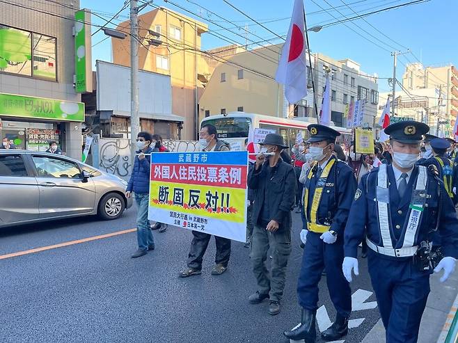 지난 4일 극우 정당인 ‘일본제일당’ 집회에 참석한 사람들이 ‘무사시노시 외국인 주민투표 조례 결사반대’라는 펼침막을 들고 도로 행진을 하고 있다. 100명 이상의 경찰(오른쪽 제복)이 동원됐다. 도쿄/김소연 특파원 dandy@hani.co.kr