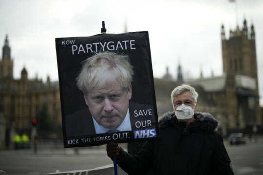 8일(현지시간) 영국 런던 의회 앞 광장에서 시위대가 보리스 존슨 총리의 얼굴이 담긴 팻말을 들고 시위를 벌이고 있다. 연합뉴스