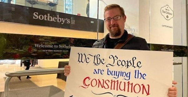 소더비 경매장 앞에 선 컨스티튜션DAO 관계자. "우리가 미국 헌법을 사는 바로 그 사람들(People)"이라고 쓴 푯말을 들고 있다. 자료=컨스티튜션DAO