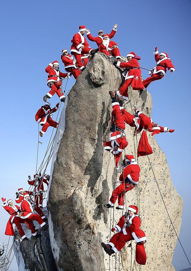 서울 북한산 만경대에서 산타 복장을 한 산악 대원들이 바위를 오르고 있다. 2019년 [연합뉴스 자료사진]