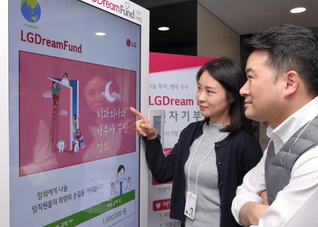 서울 LG트윈타워 빌딩에서 LG디스플레이 직원이 전자 기부함에 소개된 지역사회 이웃의 사연을 보고 사원증을 접촉해 기부하고 있다. LG디스플레이 제공
