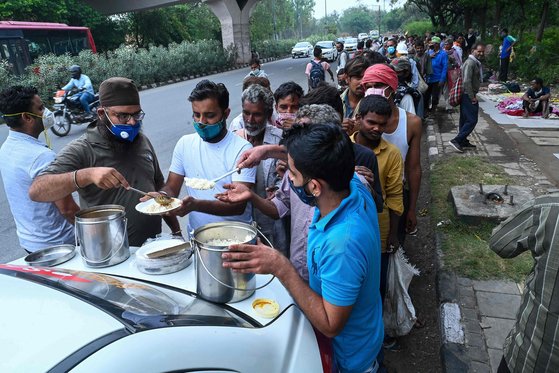 지난 5월 인도 봉쇄 당시, 일자리를 잃은 뉴델리 지역 일용직 노동자들이 자원봉사 단체가 지급하는 음식을 받고 있다. [AFP=연합뉴스]