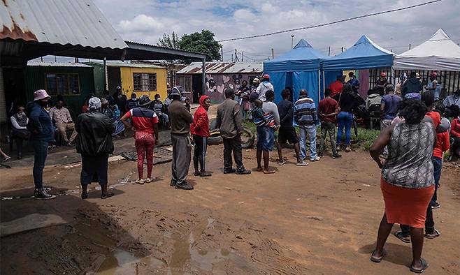 남아프리카공화국이 신종 코로나바이러스 감염증(코로나19) 오미크론 변이 확산으로 비상인 가운데 지난 8일(현지시간) 요하네스버그의 한 병원 앞에 코로나19 백신을 맞으려는 주민들이 길게 줄지어 서 있다. 요하네스버그=AFP연합뉴스