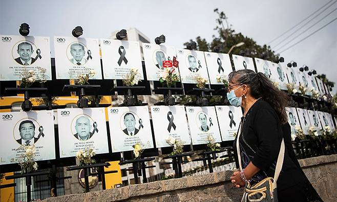 지난 8일(현지시간) 페루 수도 리마의 한 의대 앞에 신종 코로나바이러스 감염증(코로나19)으로 희생된 의사 551명을 추모하기 위한 '영웅들의 길'(Paseo de los Heroes)이 마련돼 한 시민이 숨진 의사들의 사진을 바라보고 있다. 리마=AFP연합뉴스